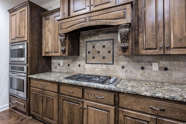 kitchen featuring tasteful backsplash, dark wood-style floors, appliances with stainless steel finishes, stone counters, and under cabinet range hood