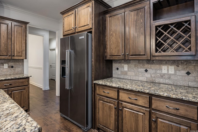 kitchen featuring dark wood finished floors, ornamental molding, high end fridge, light stone countertops, and backsplash