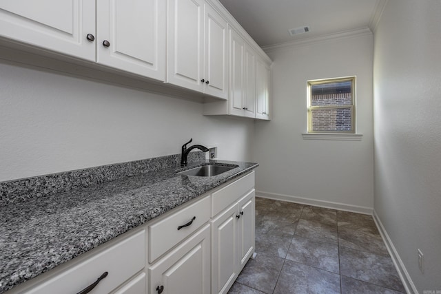 clothes washing area with crown molding, hookup for a washing machine, cabinet space, visible vents, and a sink