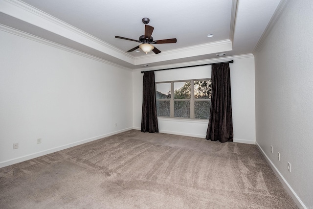 carpeted spare room featuring ceiling fan, ornamental molding, a raised ceiling, and baseboards