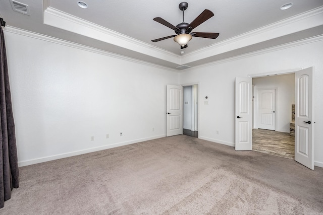 unfurnished bedroom with carpet floors, ornamental molding, a raised ceiling, and visible vents