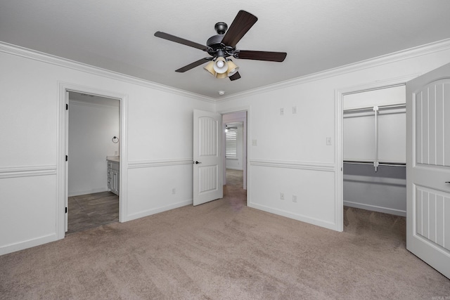 unfurnished bedroom with baseboards, ornamental molding, a closet, carpet, and a walk in closet