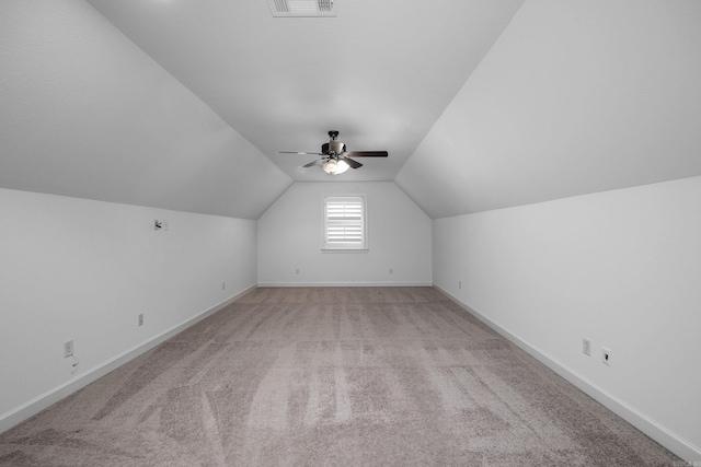 additional living space featuring light colored carpet, a ceiling fan, baseboards, vaulted ceiling, and visible vents