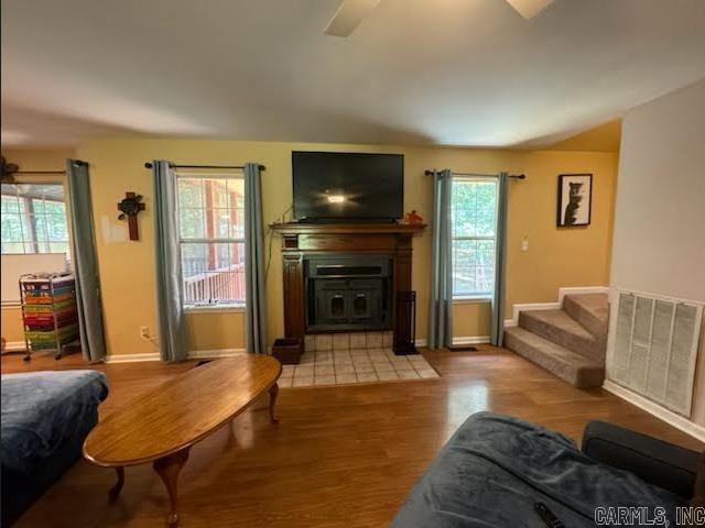 living area featuring baseboards, ceiling fan, stairway, and wood finished floors