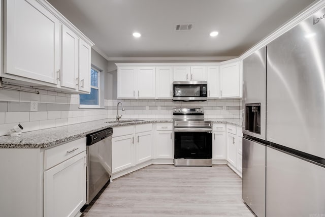 kitchen featuring visible vents, white cabinets, stainless steel appliances, crown molding, and a sink