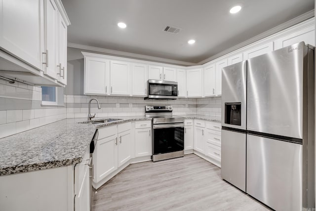 kitchen featuring stainless steel appliances, a sink, visible vents, light wood-style floors, and white cabinets