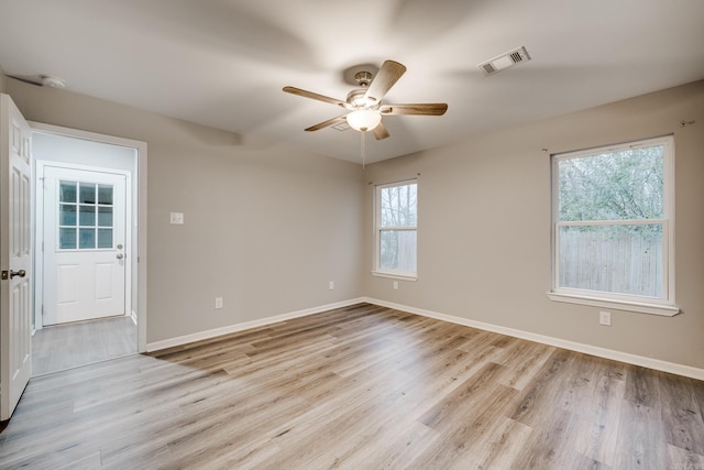 spare room featuring baseboards, visible vents, ceiling fan, and wood finished floors