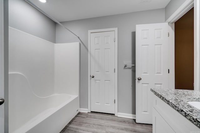 bathroom with shower / bath combination, vanity, baseboards, and wood finished floors