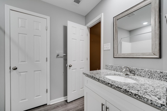 full bath featuring visible vents, vanity, baseboards, and wood finished floors