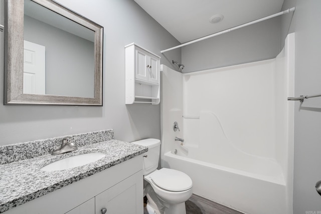 bathroom featuring toilet, tub / shower combination, wood finished floors, and vanity