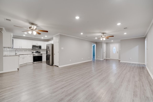 unfurnished living room with a ceiling fan, light wood-type flooring, visible vents, and a sink