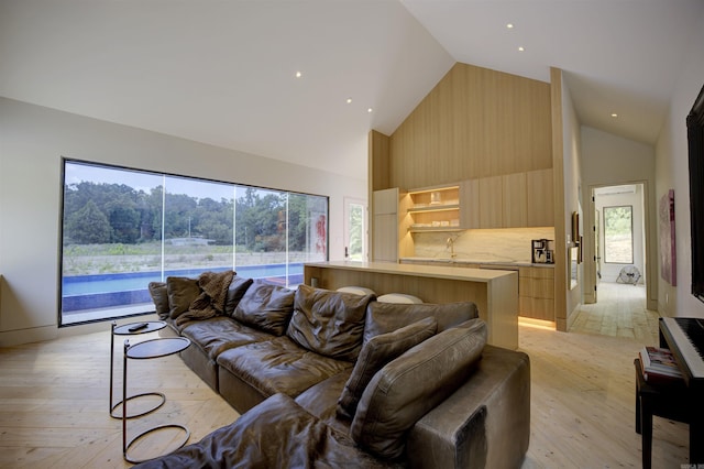 living room featuring high vaulted ceiling and light wood finished floors