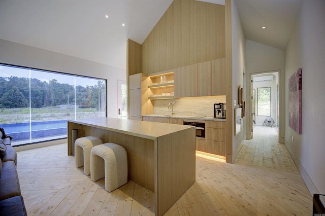 kitchen with light countertops, modern cabinets, high vaulted ceiling, and wall oven