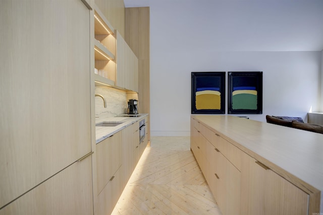 kitchen featuring tasteful backsplash, modern cabinets, a sink, and light brown cabinetry