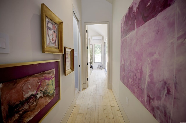 hallway with a wall mounted air conditioner and light wood-style flooring