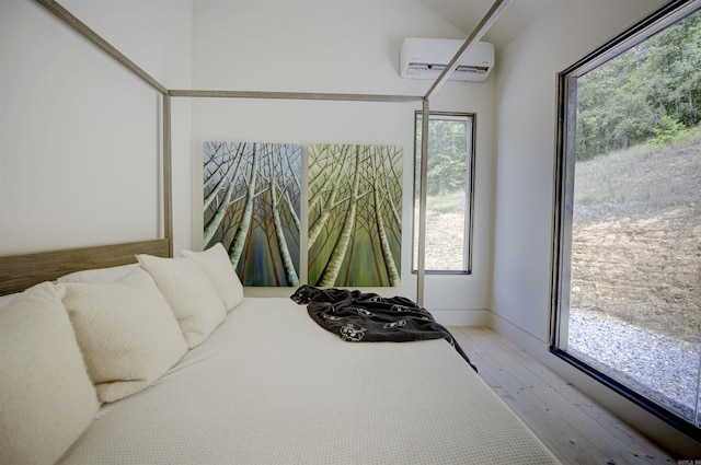 bedroom with light wood finished floors and a wall mounted air conditioner