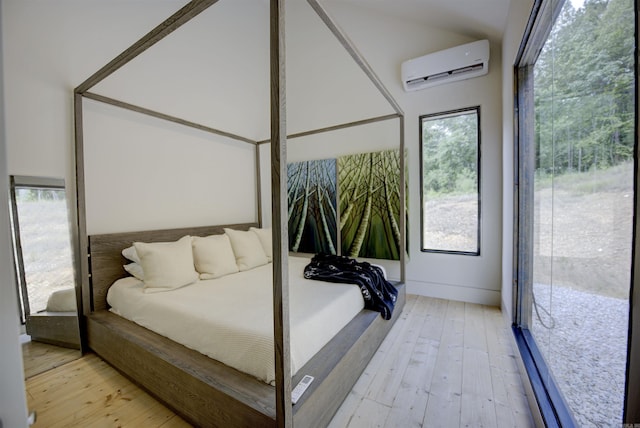 bedroom with a wall unit AC, light wood-style flooring, and multiple windows