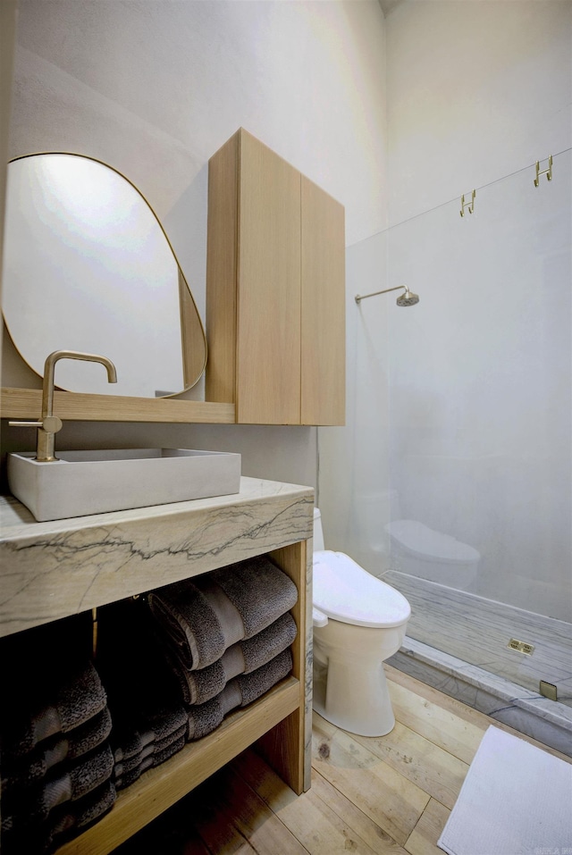 bathroom featuring wood finished floors, vanity, toilet, and walk in shower