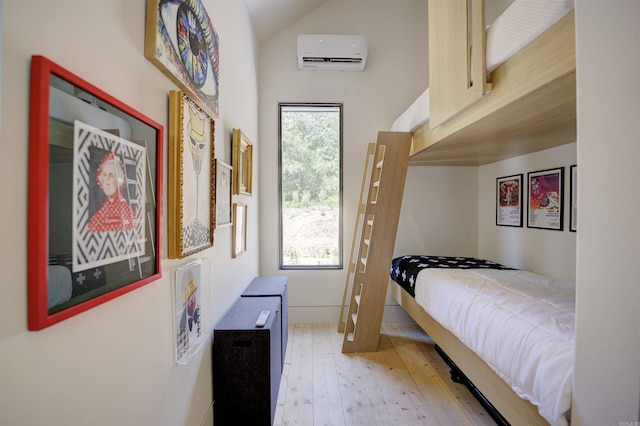 bedroom with a wall unit AC, light wood-style flooring, and vaulted ceiling