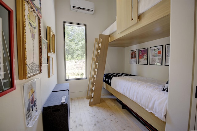 bedroom with light wood-style floors, a wall unit AC, and multiple windows