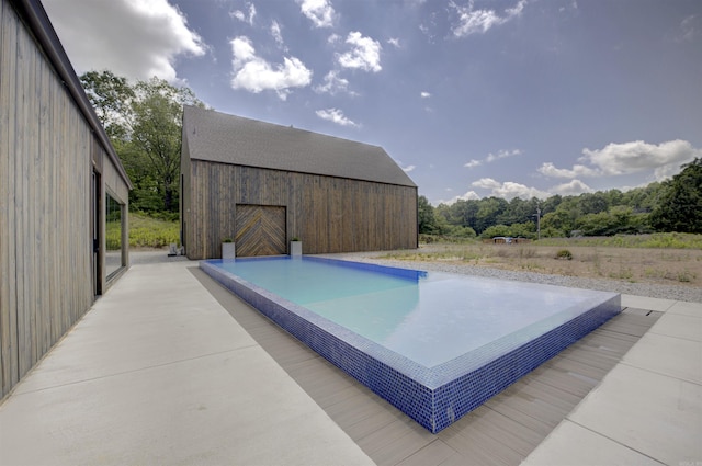 view of swimming pool with a barn and an outdoor structure