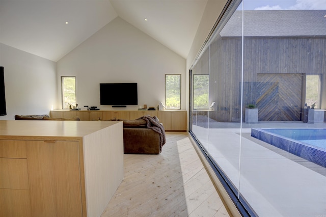 unfurnished living room featuring high vaulted ceiling, plenty of natural light, and light wood-style flooring