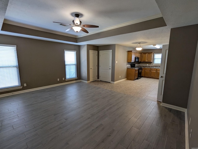 interior space featuring open floor plan, a raised ceiling, range, and brown cabinets