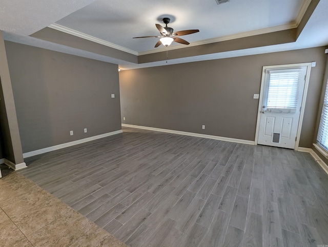 empty room featuring baseboards, a raised ceiling, and wood finished floors