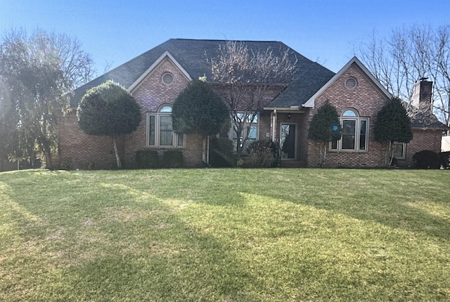 view of front of home with a chimney, a front lawn, and brick siding