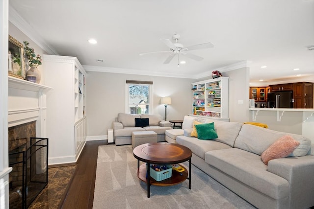 living area featuring dark wood-type flooring, recessed lighting, a fireplace with raised hearth, and crown molding