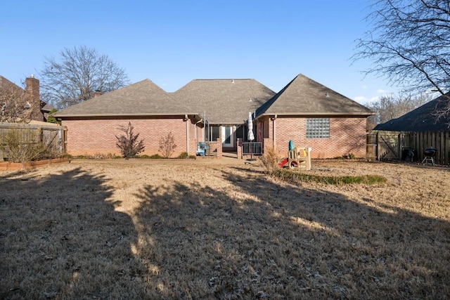 rear view of house with brick siding and fence