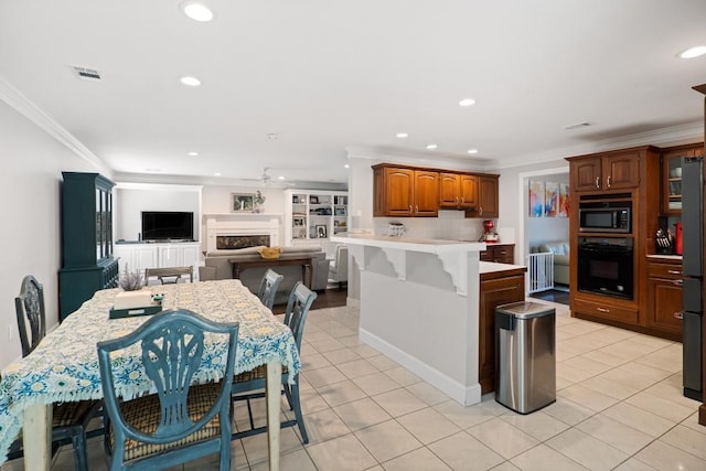 kitchen with crown molding, a fireplace, a peninsula, and black appliances