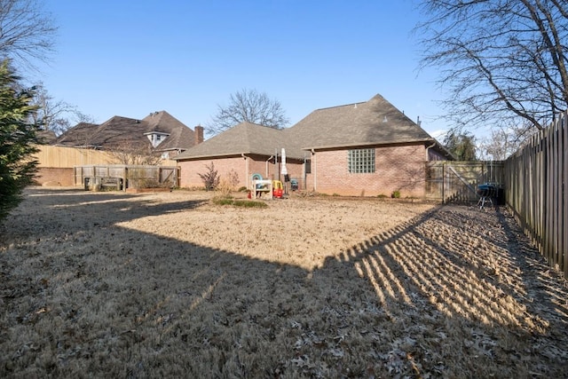 rear view of property with brick siding and a fenced backyard