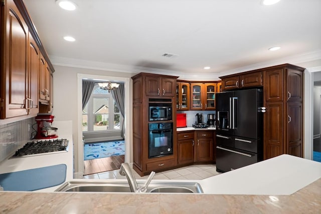 kitchen with ornamental molding, a sink, backsplash, and black appliances