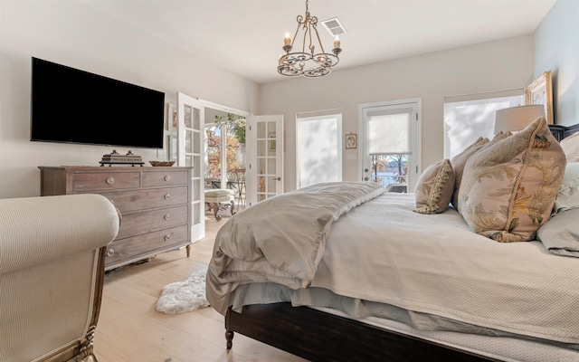 bedroom featuring access to exterior, light wood-type flooring, a chandelier, and multiple windows