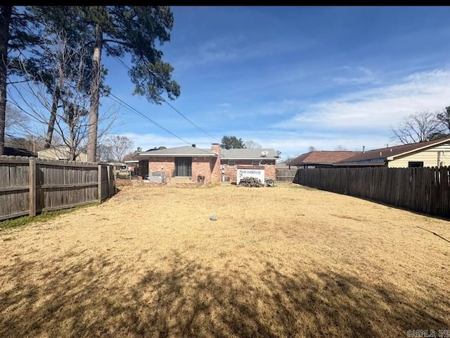 rear view of property with a fenced backyard and a yard