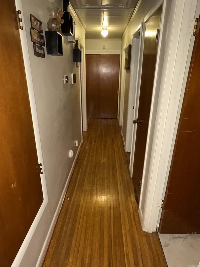 corridor featuring baseboards and hardwood / wood-style flooring