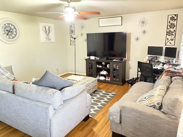 living area with ornamental molding, ceiling fan, baseboards, and wood finished floors