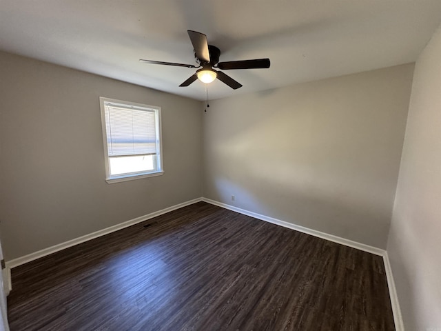 empty room featuring ceiling fan, dark wood-type flooring, and baseboards