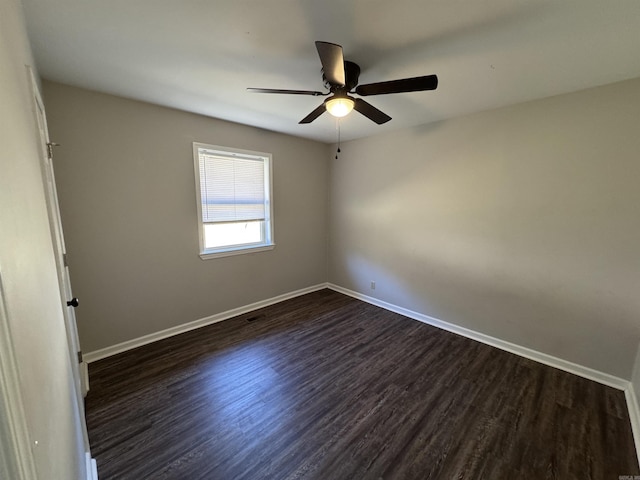 empty room with ceiling fan, baseboards, and dark wood-type flooring