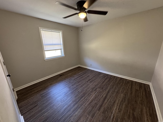 spare room featuring dark wood-type flooring, ceiling fan, and baseboards