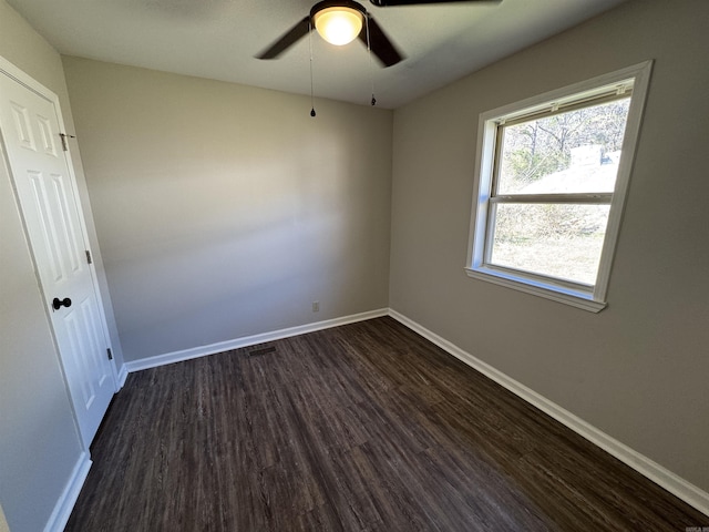 unfurnished room featuring dark wood-style flooring, ceiling fan, and baseboards