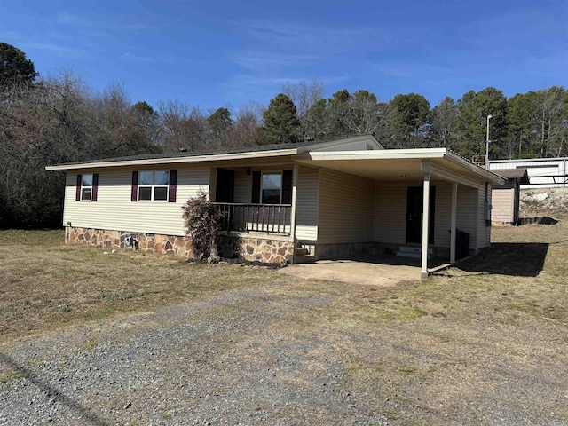 view of front facade with dirt driveway, a porch, crawl space, and an attached carport