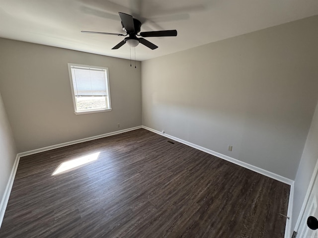 empty room with dark wood-style floors, ceiling fan, visible vents, and baseboards