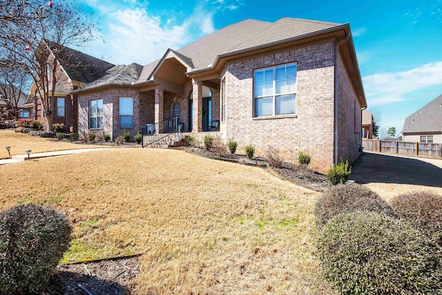 view of front of property with roof with shingles, a front lawn, and brick siding