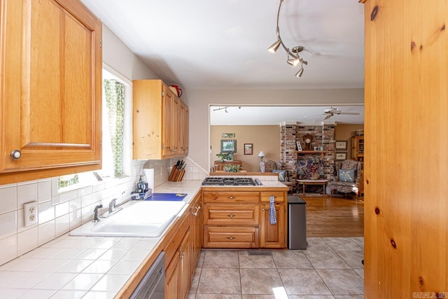 kitchen featuring tile countertops, light tile patterned floors, backsplash, open floor plan, and a sink