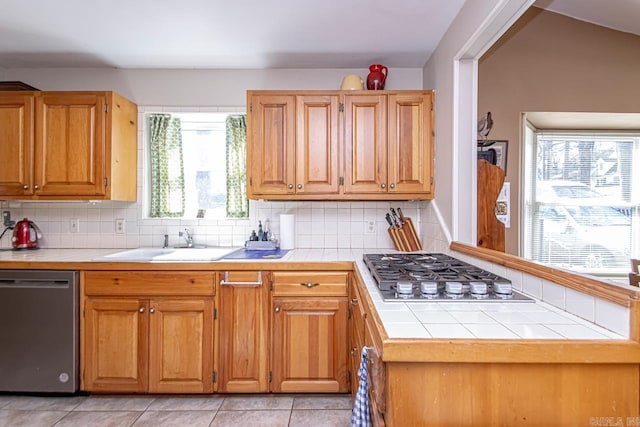 kitchen featuring stainless steel appliances, a sink, tile counters, and decorative backsplash