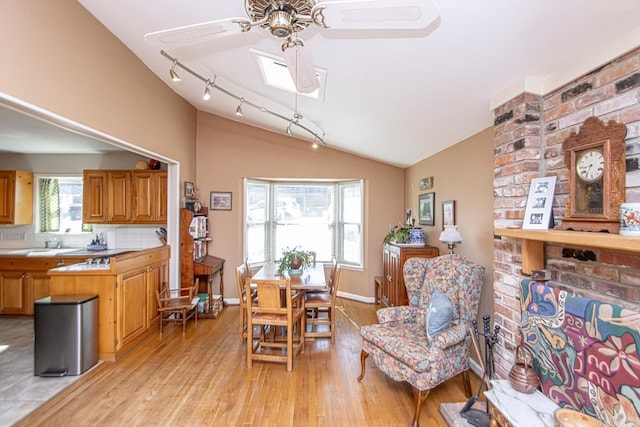 interior space with lofted ceiling with skylight, ceiling fan, baseboards, and light wood-style floors