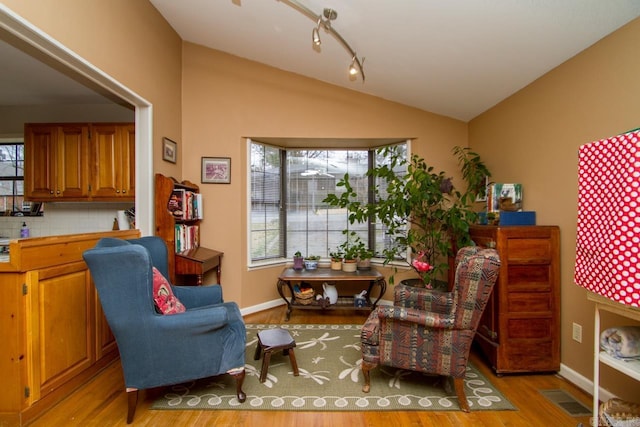 sitting room featuring lofted ceiling, baseboards, visible vents, and light wood finished floors