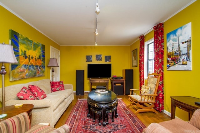 living room with ornamental molding, rail lighting, baseboards, and wood finished floors